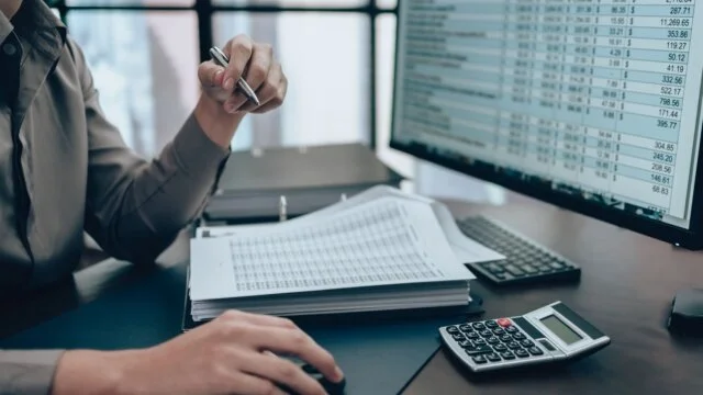 Person at desk working on data and spreadsheets.
