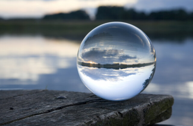 Glass ball on a footbridge at the foreground of a photo where everything else is blurry.